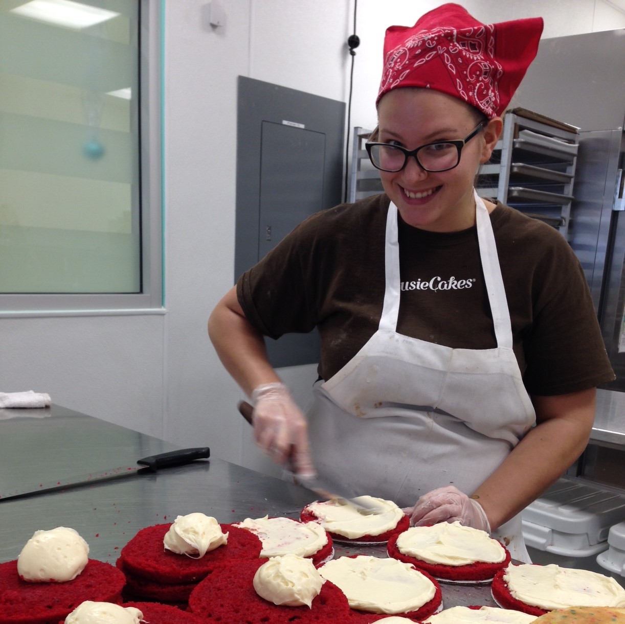 Bakery worker frosting red velvet cake layers